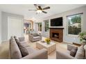 Bright living room featuring a cozy brick fireplace, ceiling fan and neutral colored furniture at 1765 S Kline Way, Lakewood, CO 80232