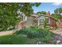 Beautifully landscaped front yard featuring mature shade trees, rocks, green grass, and colorful plantings at 11245 San Joaquin Rdg, Littleton, CO 80127