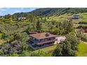 Stunning aerial view of a multi-level home with wraparound deck nestled in a lush, green landscape at 1380 Oak Valley Rd, Sedalia, CO 80135