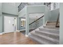 Grand entryway with soaring ceilings, hardwood floors, carpeted stairs, and iron railings showcases a modern design at 7837 Aravon Ct, Lone Tree, CO 80124