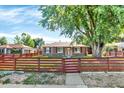 Charming single-story home with a brick facade, inviting front yard, and a red horizontal wooden fence at 2810 Oneida St, Denver, CO 80207