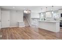 Open floor plan of the living room, showcasing stairs, kitchen, hardwood floors, and a chandelier at 9442 W Walden Ave, Littleton, CO 80128
