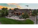 Expansive backyard features stone patio with a built-in fire pit and seating, manicured lawn, and the house at sunset at 7130 Independence St, Arvada, CO 80004