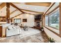 Inviting living room with stone fireplace, exposed beams, large windows, and an open layout to kitchen at 7552 Miller Ct, Arvada, CO 80005