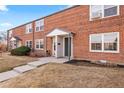 Traditional brick townhome exterior with tidy front lawn and covered entryway at 6002 E 29Th Ave, Denver, CO 80207