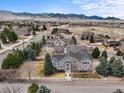 Stunning gray two-story home featuring a white fence, lush lawn, mature trees, and picturesque mountain views at 5753 Secrest Ct, Golden, CO 80403
