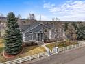 Charming home with stone accents, a manicured lawn, mature trees, and a white picket fence at 5753 Secrest Ct, Golden, CO 80403