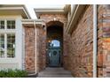 Inviting front entrance featuring a solid wood door, brick archway, and covered porch, creating a warm welcome at 924 Glen Oaks Ave, Castle Pines, CO 80108