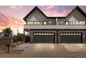 Modern townhome showcasing brick facade, two-car garage, and a driveway, set against a vibrant sunset backdrop at 5240 N Raleigh St, Denver, CO 80212