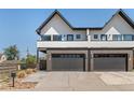 Modern townhome with a brick facade, black trim, two-car garage, and a large driveway at 5240 N Raleigh St, Denver, CO 80212