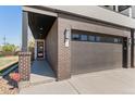 Close-up of a modern townhome with a brick facade, two-car garage, and a covered entryway with a red door at 5240 N Raleigh St, Denver, CO 80212