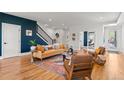 Bright living room features hardwood floors, modern furniture, and a striking blue accent wall with an open stairway at 5240 N Raleigh St, Denver, CO 80212