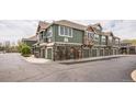Row of townhomes with green siding, stone accents, and convenient garage parking for each unit at 7080 Simms St # 105, Arvada, CO 80004