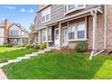 Inviting exterior featuring a well-kept lawn, brick accents, and steps to the townhouse's entrance at 17108 E Whitaker Dr # B, Aurora, CO 80015