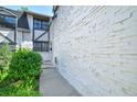 Exterior shot of a white brick townhome, showcasing the side entrance and manicured bushes at 5821 E Ithaca Pl, Denver, CO 80237