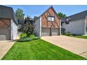 Charming Tudor-style townhome with a brick and white exterior, two-car garage, and well-manicured lawn at 5821 E Ithaca Pl, Denver, CO 80237