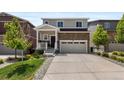 Attractive two-story home featuring a stone facade, a two-car garage, and lush front yard landscaping at 5297 Blue Lunar Ln, Castle Rock, CO 80104