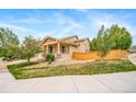 Tan two-story home showing manicured front yard, covered porch, and wood fencing at 4850 Bluegate Ln, Highlands Ranch, CO 80130