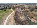 Scenic aerial view of a paved path alongside a serene river, surrounded by natural landscape and open fields at 18995 E Bellisario Creek Pl, Parker, CO 80134
