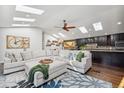 Open concept living room with skylights flows into the kitchen with dark cabinets at 6995 S Kendall Blvd, Littleton, CO 80128