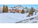 Two-story house with snow-covered yard, visible walkway, and mature trees at 2325 15Th Ave, Longmont, CO 80503