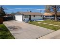 Charming single-story home features a wide driveway, lush lawn, and a classic white brick exterior at 7621 Granada Rd, Denver, CO 80221