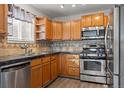 Bright kitchen features stainless steel appliances, wooden cabinets, and neutral backsplash at 3230 S Decatur St, Denver, CO 80236