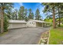 Exterior view showing paved driveway, carport and garage nestled amongst mature trees at 26752 Vosler St, Conifer, CO 80433