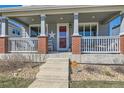 Inviting front porch with brick accents, a white railing, and space to relax and enjoy the outdoors at 12881 Park Creek Way, Firestone, CO 80504