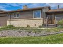 Close up exterior shot of cozy home with brick accents, a well-manicured lawn, and inviting front entrance at 7245 W 70Th Ave, Arvada, CO 80003