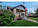 Charming brick home featuring a cozy front porch and landscaped yard with colorful flowers at 1399 Newton St, Denver, CO 80204