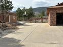 Large concrete driveway next to brick home, including a storage shed and basketball hoop at 8229 Red Rock Pl, Larkspur, CO 80118