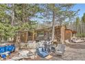 Log cabin exterior view featuring trees, debris, furniture and weathered wood at 1645 Little Bear Creek Rd, Idaho Springs, CO 80452