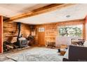 Living room featuring wood paneled walls, wood-burning stove and natural lighting at 1645 Little Bear Creek Rd, Idaho Springs, CO 80452