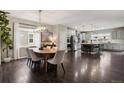 Open concept dining area with hardwood floors, modern lighting, and kitchen view at 11008 Hayloft St, Parker, CO 80134