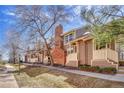 A sunny townhouse exterior shows brown siding, a brick chimney, covered porches and neat landscaping at 2062 S Helena St # B, Aurora, CO 80013