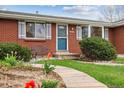 Close up of the brick exterior and front yard featuring lush greenery and a garden bench at 6609 W Mexico Pl, Lakewood, CO 80232