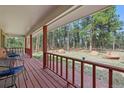 Covered porch with multiple seating arrangements surrounded by mature trees at 17720 Canterbury Dr, Monument, CO 80132