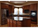 Modern kitchen with stainless steel appliances, granite countertops, central island, and ample wooden cabinetry at 6368 S Walden Way, Aurora, CO 80016