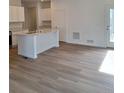 Bright open kitchen with stainless steel appliances, a large island, white cabinets, and hardwood floors at 15267 Fillmore St, Thornton, CO 80602