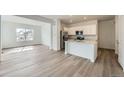 Open-concept living space with wood-look floors and a modern kitchen at 15267 Fillmore St, Thornton, CO 80602