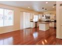 Spacious kitchen features white cabinets, an island, stainless appliances, and hardwood floors at 20768 Randolph, Denver, CO 80249
