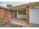 Covered front porch with brick columns leads to the front door and attached garage at 678 S Oswego Ct, Aurora, CO 80012