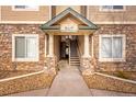 Covered entrance featuring stone accents and wooden staircase, offers a welcoming feel to the condos at 9390 W Chatfield Pl # 104, Littleton, CO 80128