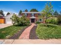 Attractive brick home featuring a walkway to the front door, set amongst a well-manicured lawn at 6953 S Prescott St, Littleton, CO 80120