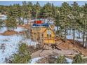 Stunning two-story home with a wooden deck, two car garage, and paved driveway surrounded by mature trees and snowy landscapes at 643 Aspen Rd, Golden, CO 80401