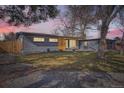 Charming single-story home at dusk with a well-maintained lawn, modern design, and attached garage at 9309 Highland Pl, Arvada, CO 80002