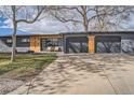 Stylish single-story home featuring an attached two-car garage and modern wood detailing at 9309 Highland Pl, Arvada, CO 80002