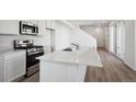 Close up of kitchen featuring white cabinets, quartz countertop island, and stainless steel appliances at 1222 Penner Dr, Erie, CO 80026