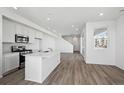 Open kitchen featuring white cabinets, a center island, stainless steel appliances, and wood-look floors at 1222 Penner Dr, Erie, CO 80026